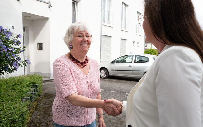 Dagmar Peilnsteiner begrüßt per Handreichung eine ältere Dame.
